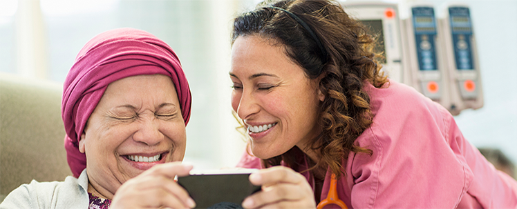 Patient and nurse looking at mobile device and smiling