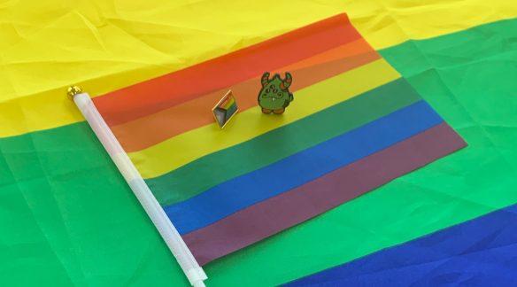 3i Monster and Pride flag pins sitting on Pride flag.