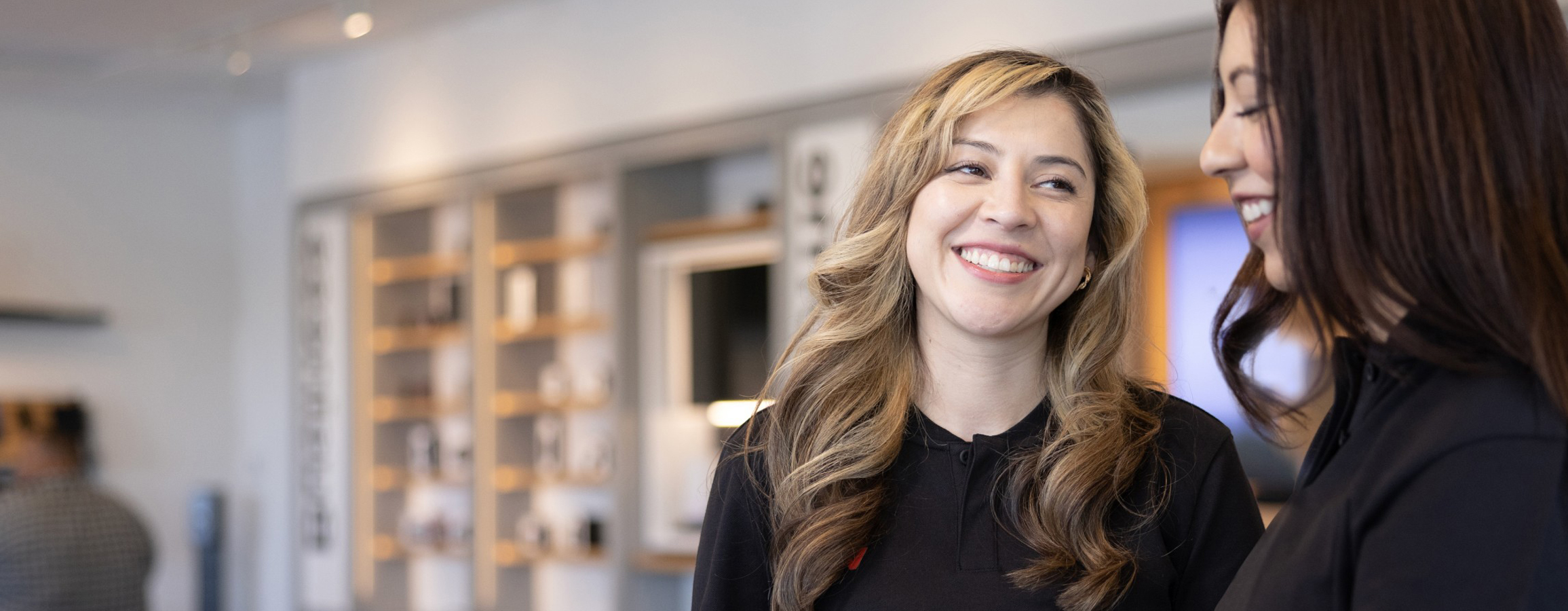 Two Verizon Retail Rockstars talking and smiling at each other in a Verizon retail store.