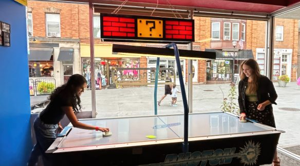 Two BNO staff members playing air hockey at an arcade.