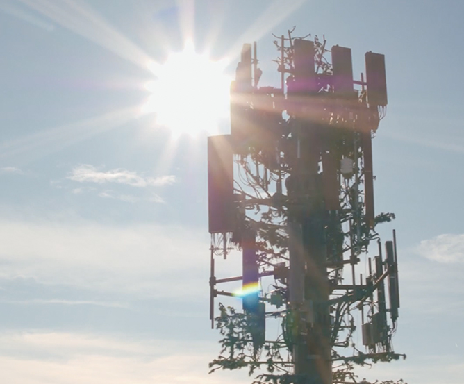 A Verizon communications tower standing in front of the sun.