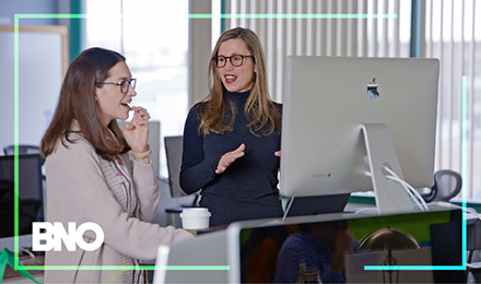 Two BNO employees reviewing a project on a monitor.